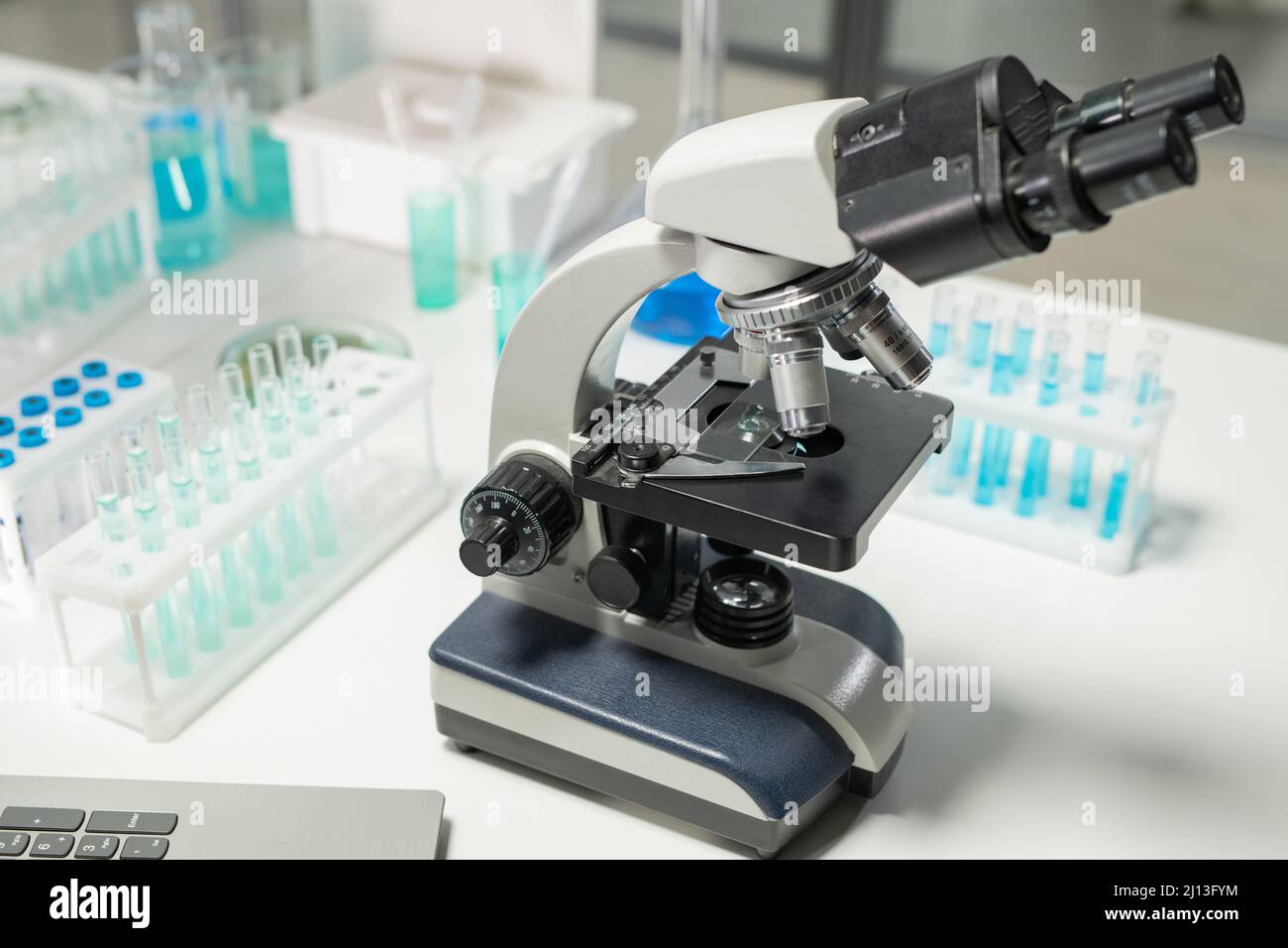 Microscope surrounded by groups of flasks containing blue liquid