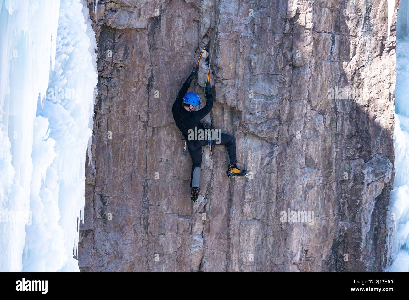 A sport climber on a mixed climb, using ice axes and crampons to climb