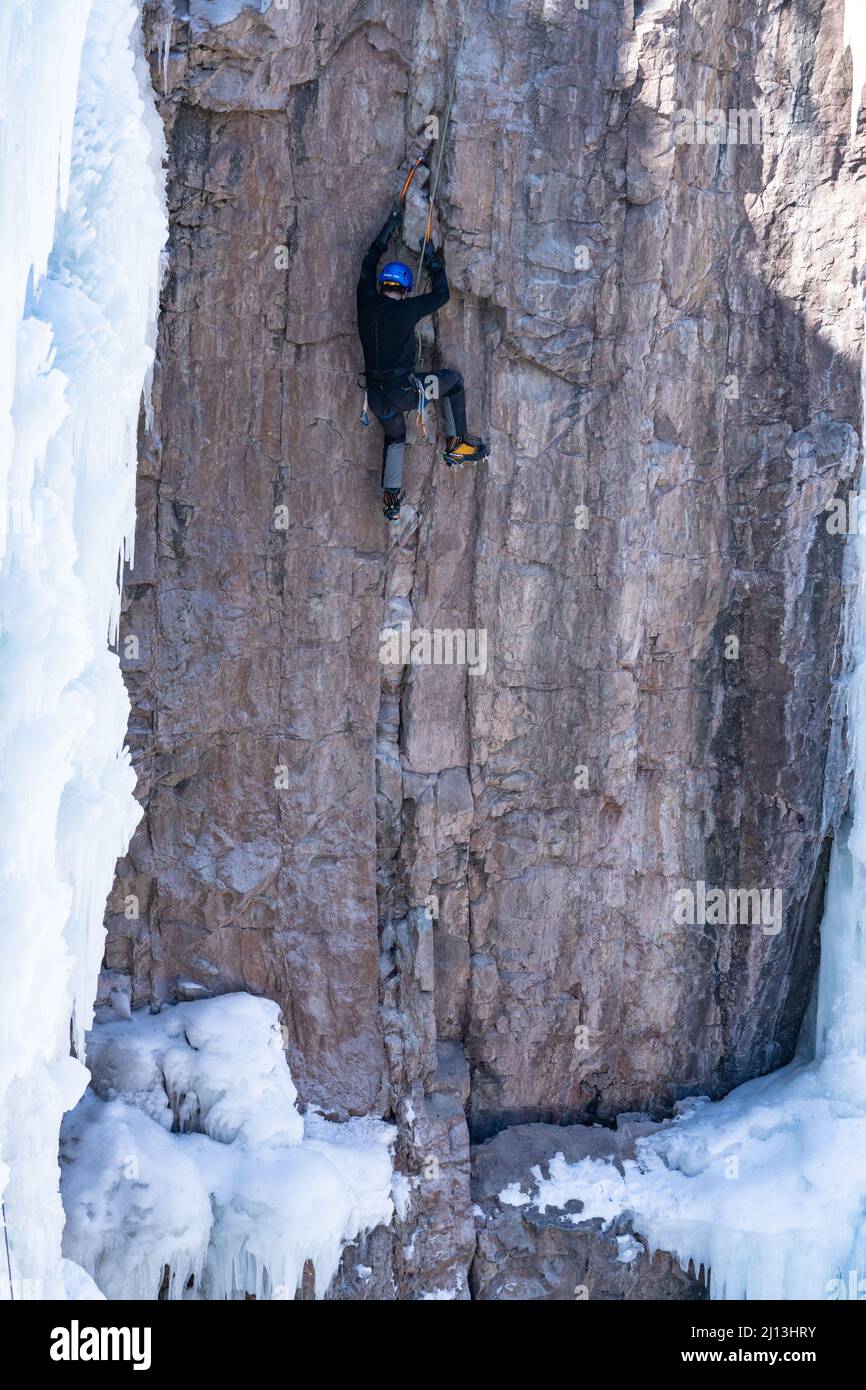 A sport climber on a mixed climb, using ice axes and crampons to climb