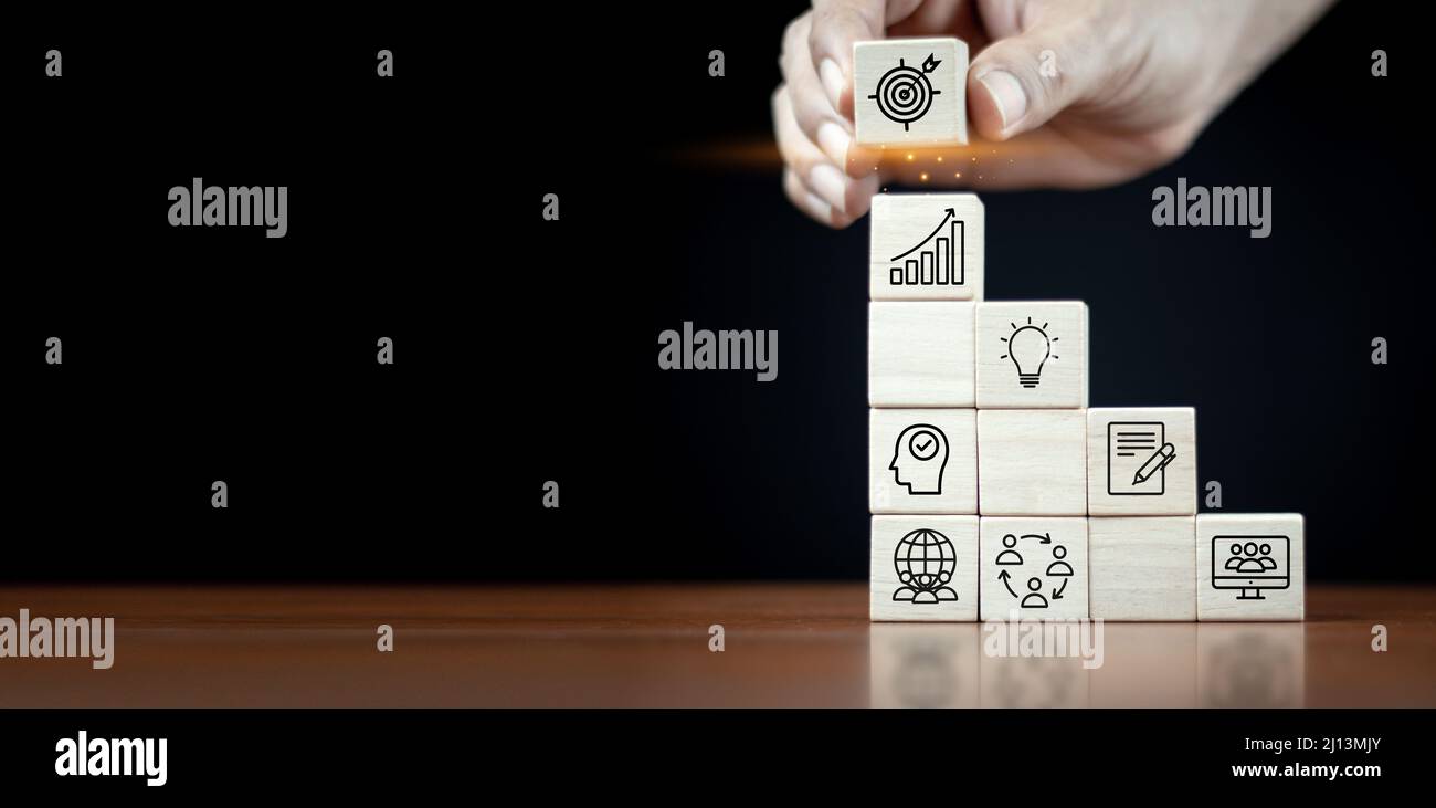 Hand placing wooden blocks with icons achieve element goals. business ...