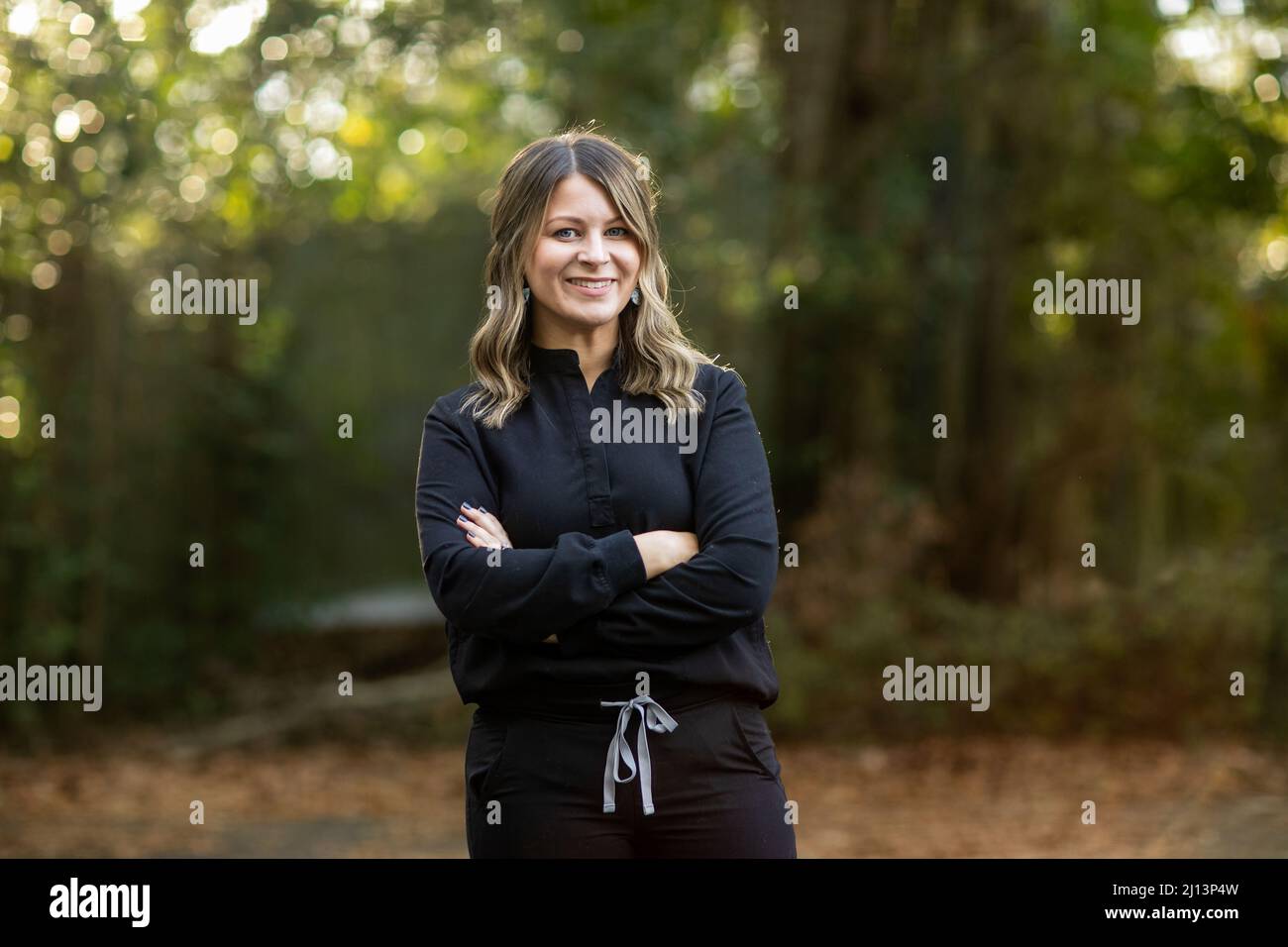 A young cosmetologist standing outside among green trees for a headshot with copy space Stock Photo