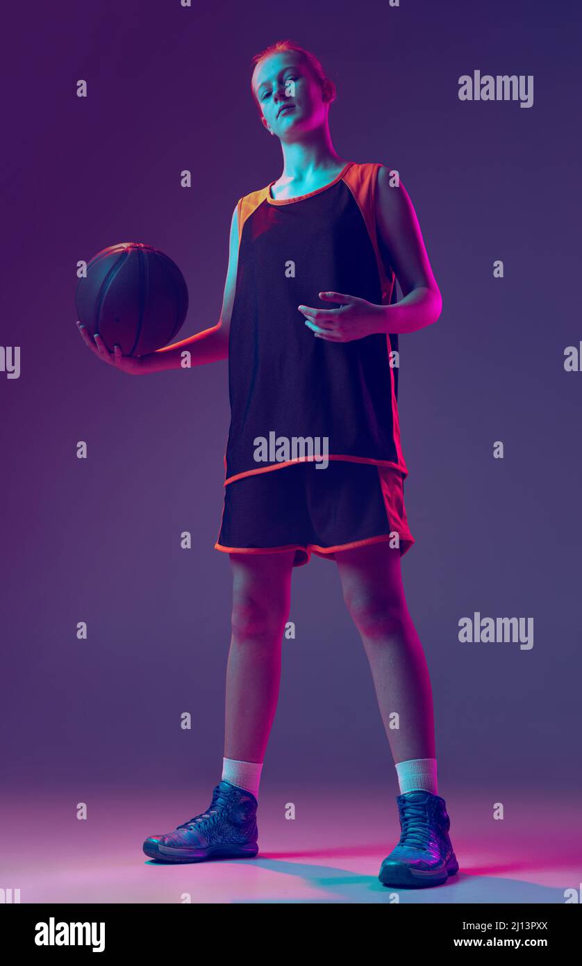 Portrait of girl, teenager, basketball player in uniform posing with ball shoulder isolated over pink purple background in neon. Champion Stock Photo - Alamy