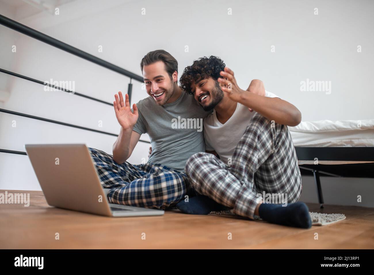 Cheerful biracial couple greeting someone via Skype Stock Photo