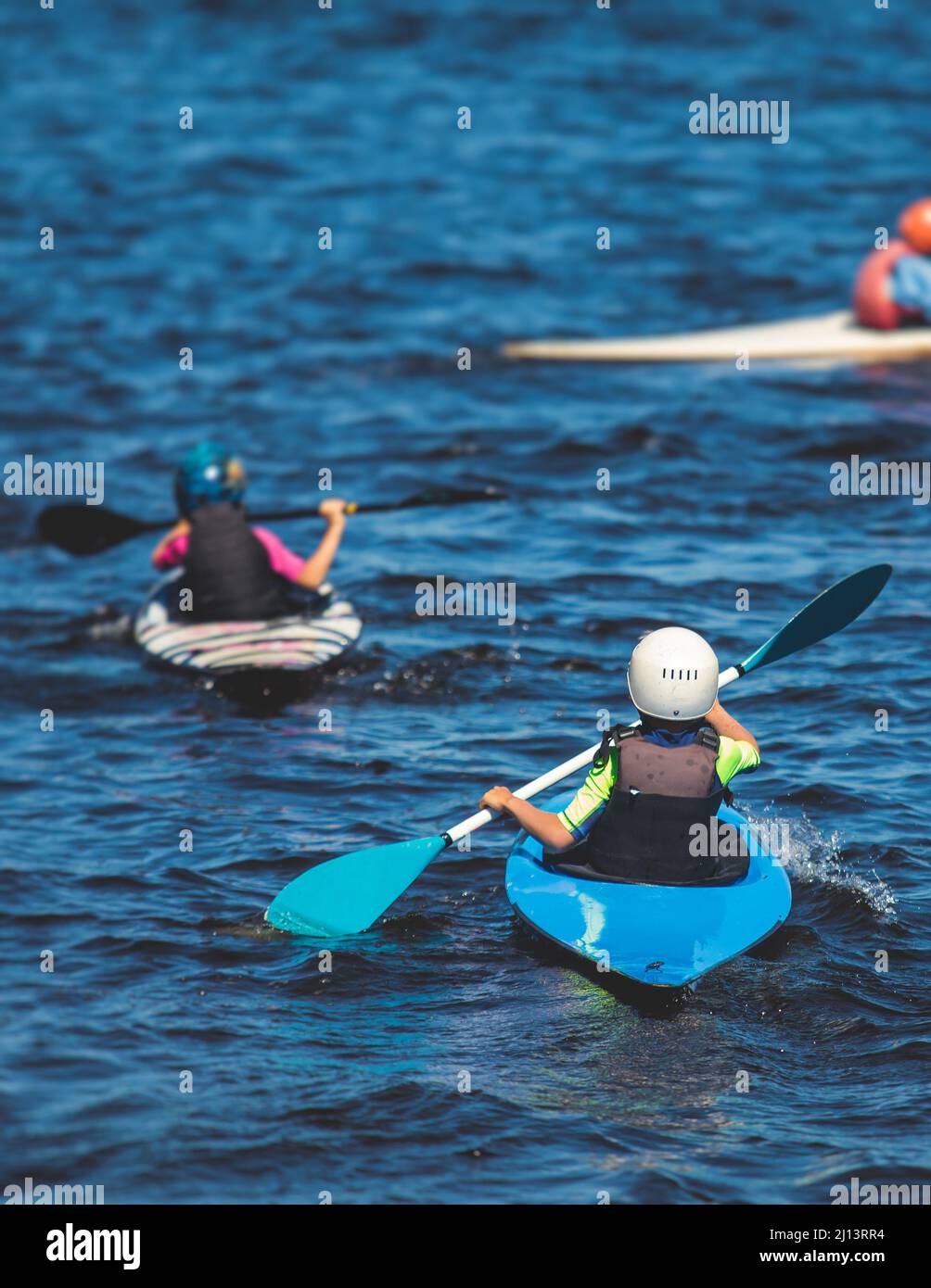 Kids learn kayaking, canoeing whitewater training in the lake river, children practicing paddling, yound kayakers in a summer camp Stock Photo