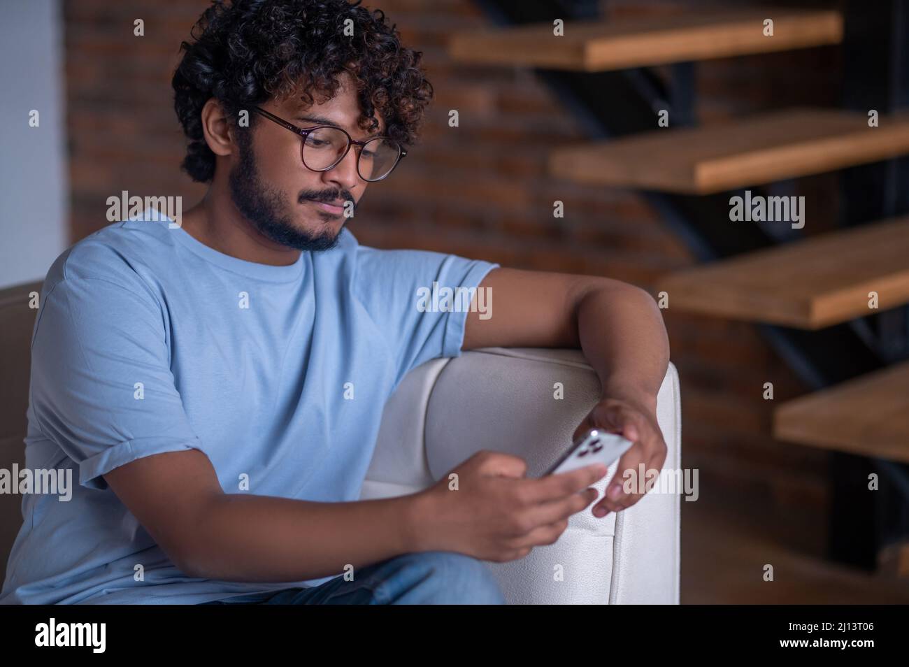 Tranquil concentrated guy looking at his cellphone screen Stock Photo