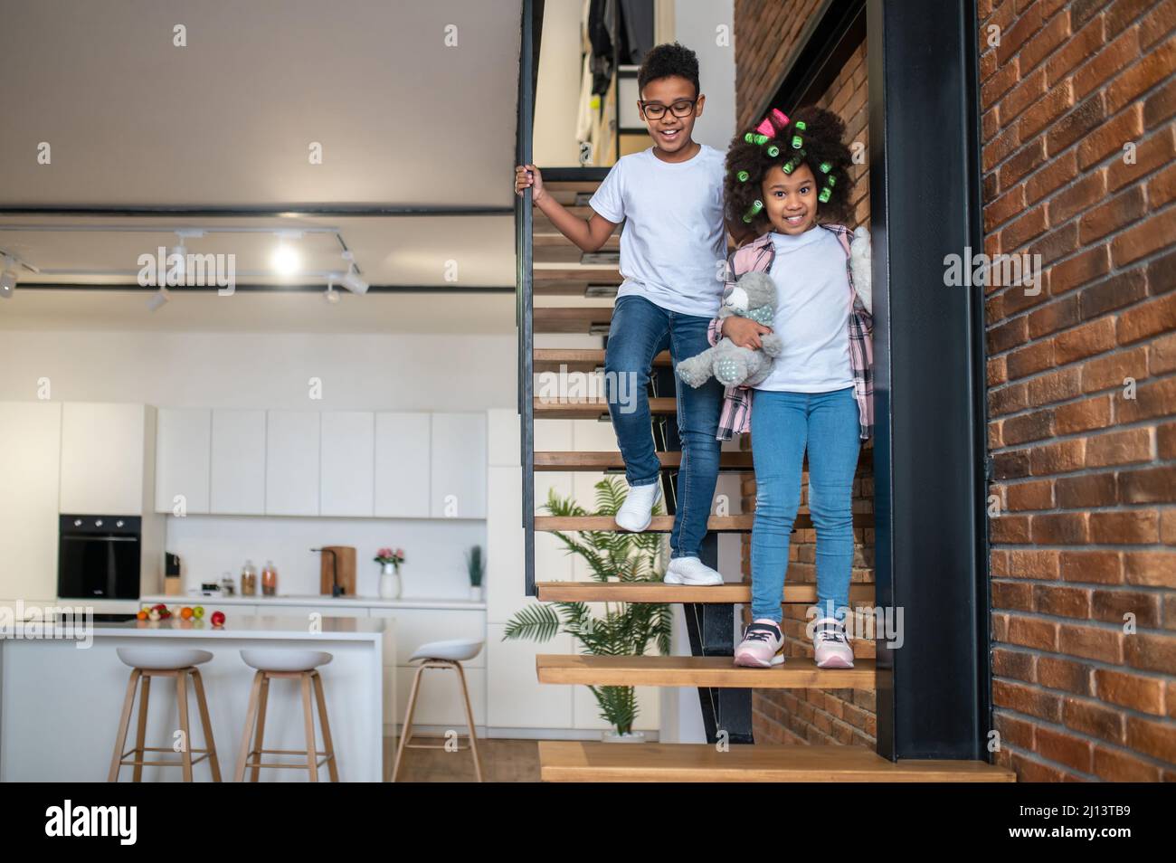 Boy and girl going down stairs at home Stock Photo