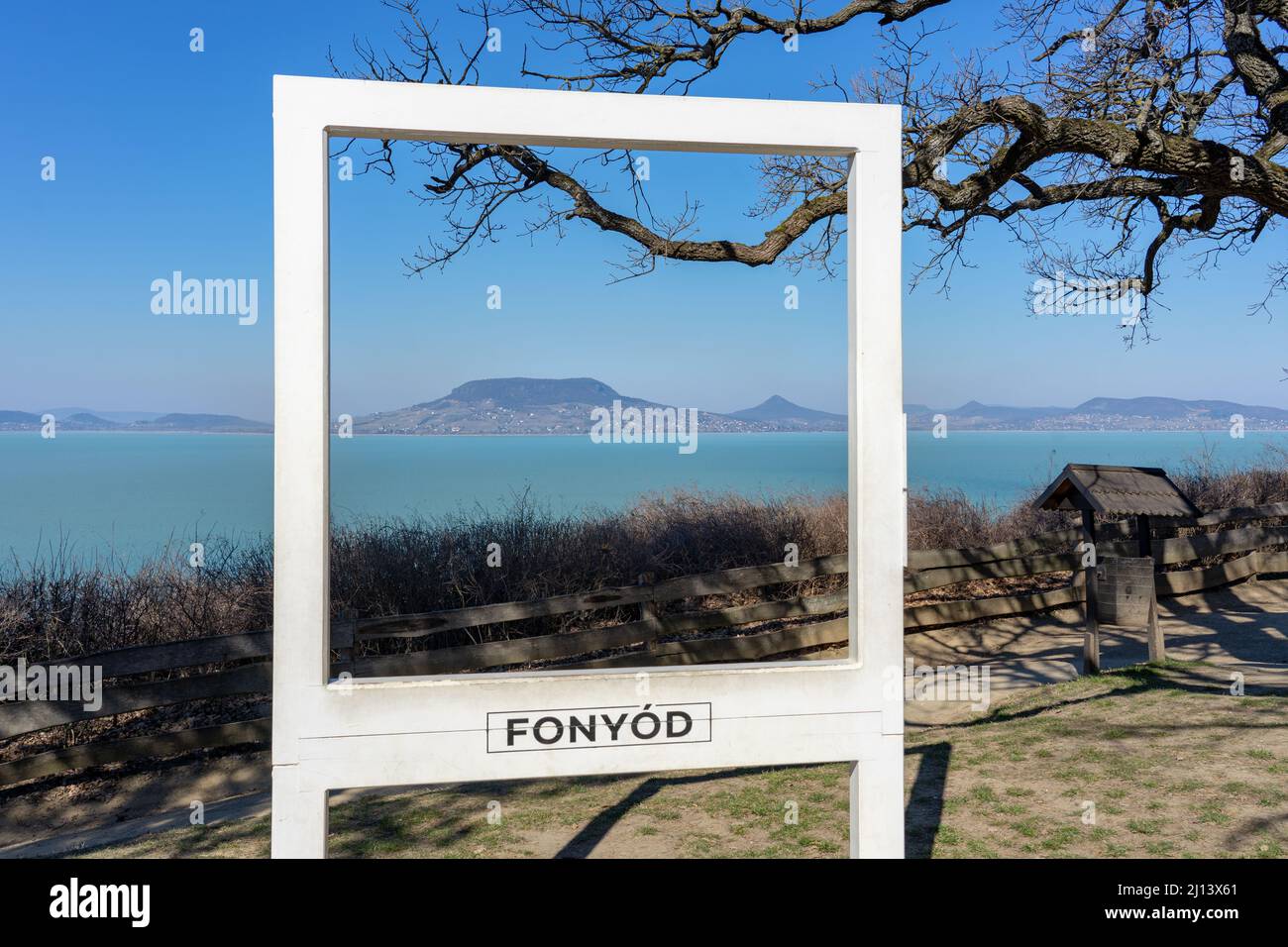 https://c8.alamy.com/comp/2J13X61/beautiful-szaplonczay-promenade-with-lake-balaton-landscape-in-fonyd-hungary-with-badacsony-hill-in-white-photo-frame-with-fonyod-sign-2J13X61.jpg
