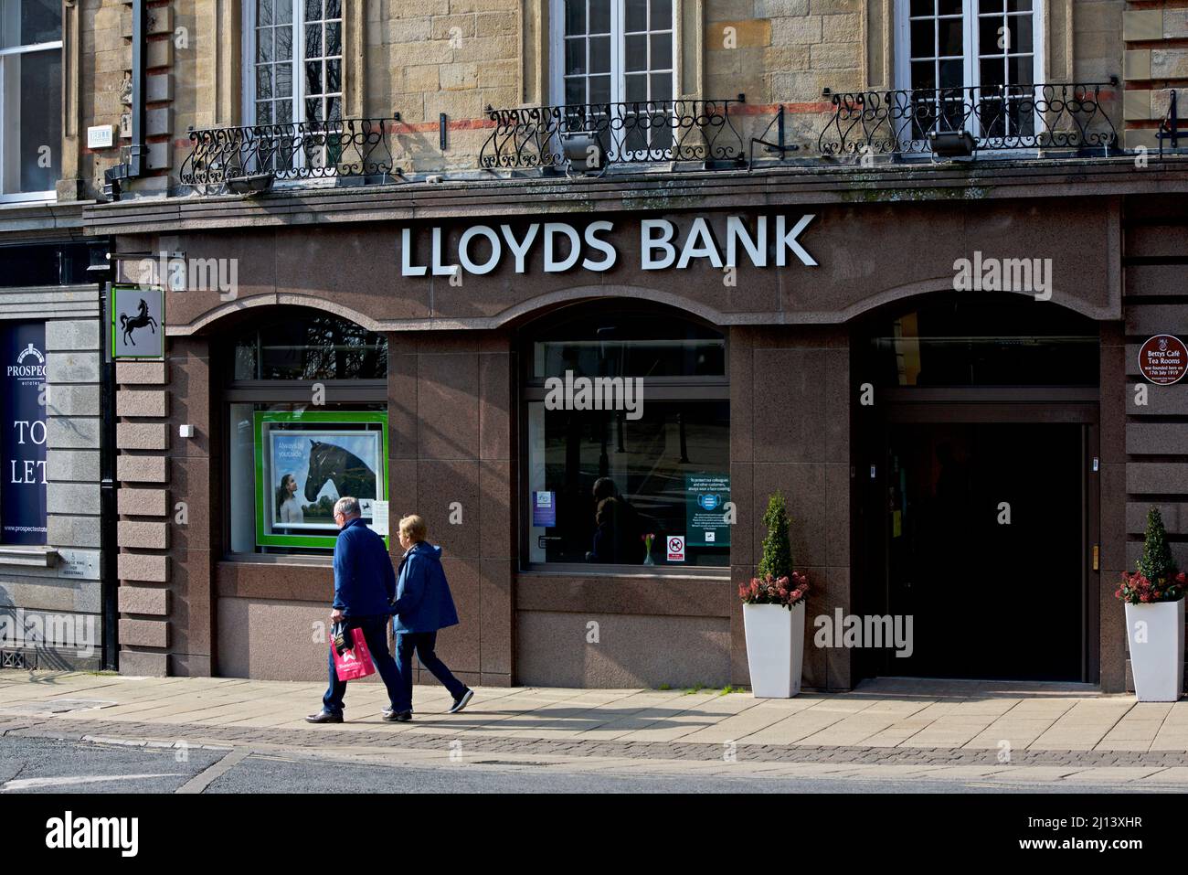 Man and woman walking past branch of Natwest bank, on Cambridge Crescent, Harrogate, North Yorkshire, England UK Stock Photo
