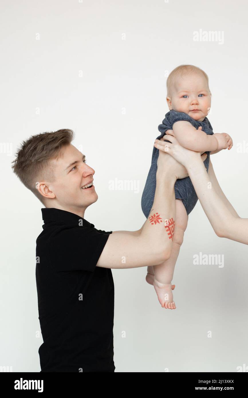 Vertical shot of glad young man, father, holding cute little baby, caring woman hands. Surrogate maternity, awaiting kid Stock Photo