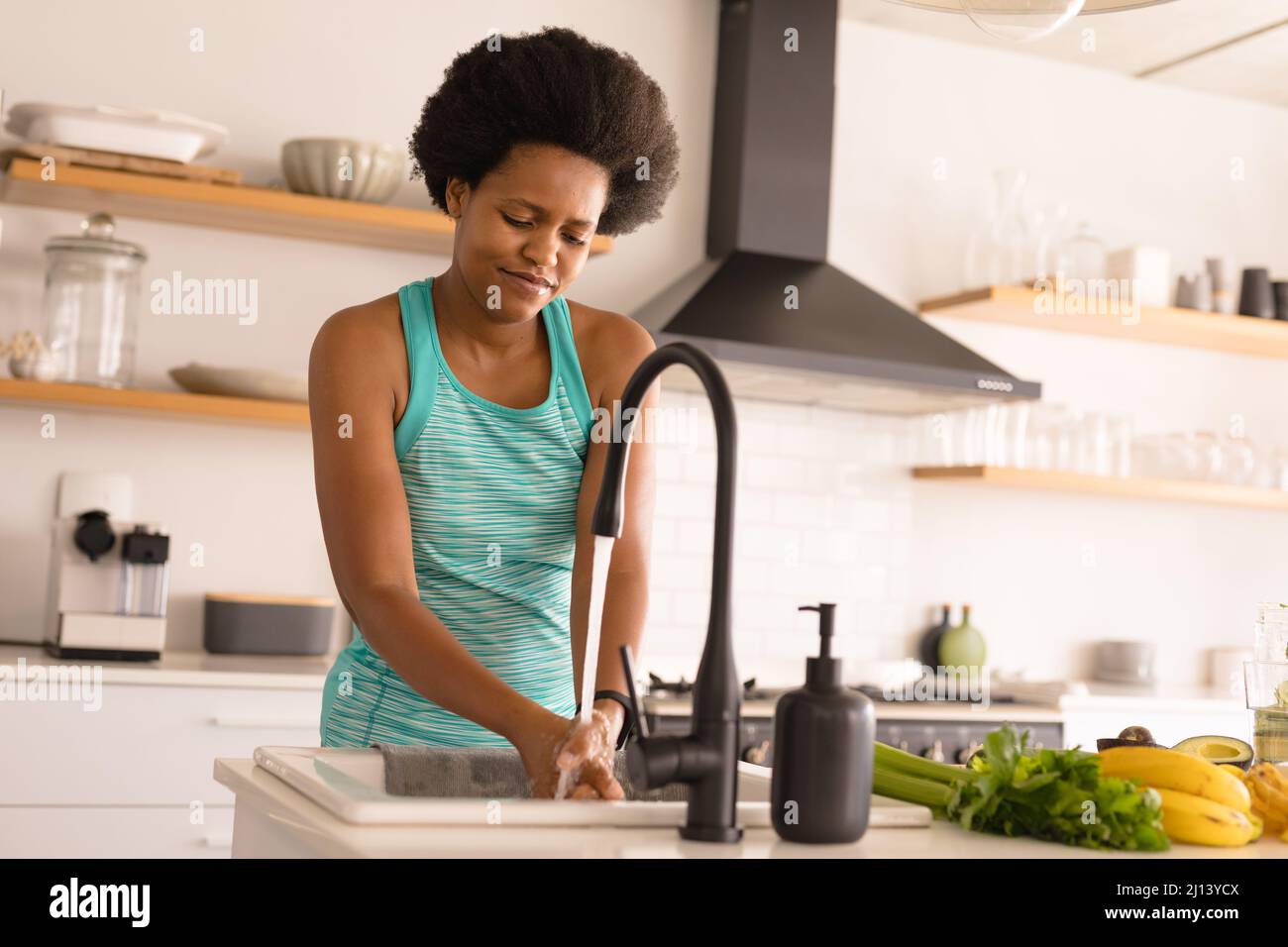 Mid adult african american woman washing hands while preparing food at home Stock Photo