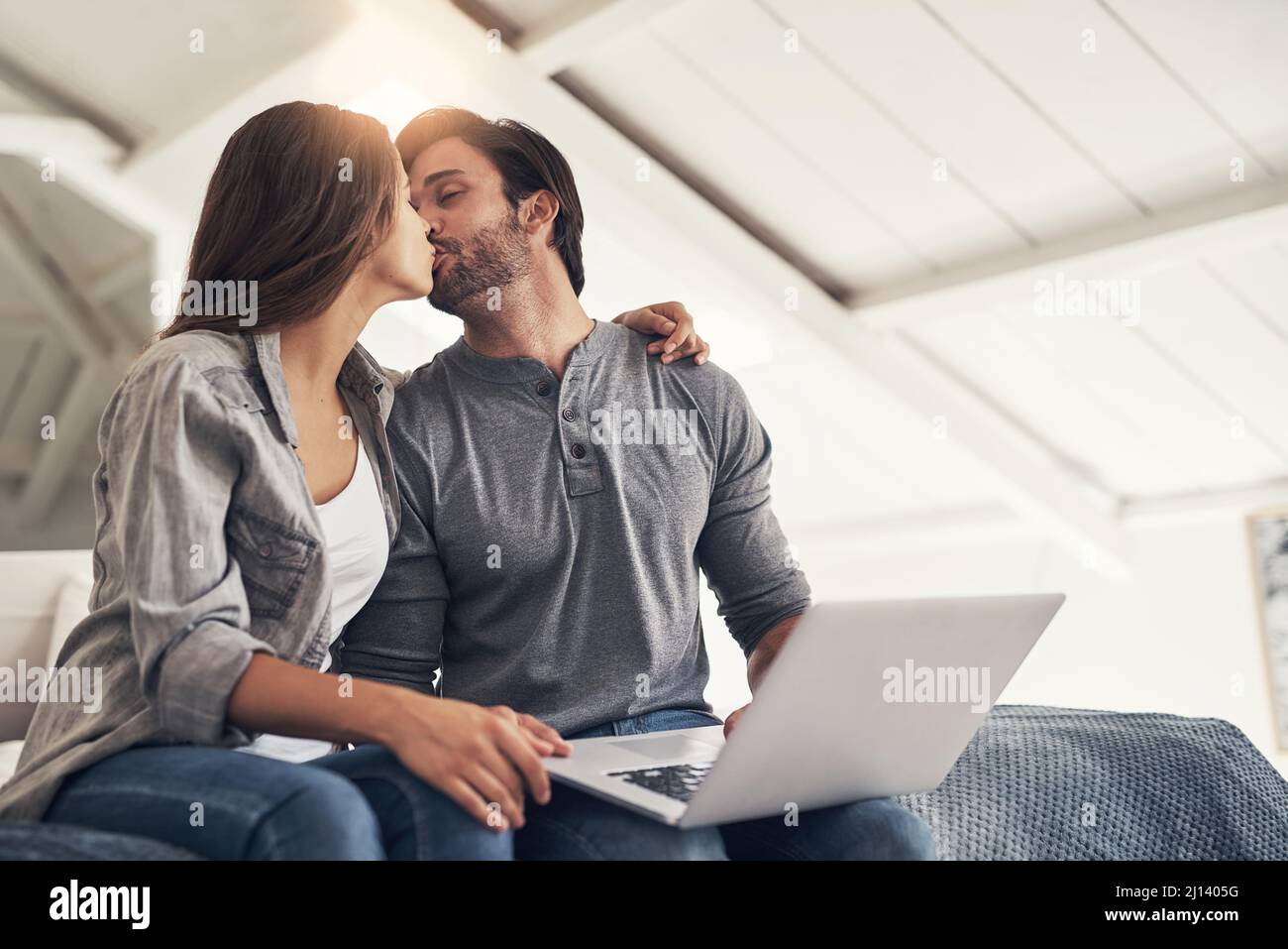 Snogging before we start blogging. Shot of an attractive young couple spending quality time at home. Stock Photo