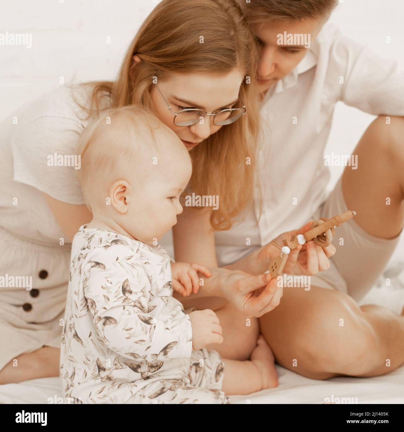 Young family spending time together, mother, father newborn baby. Showing wood toys, delayed psychological development. Stock Photo
