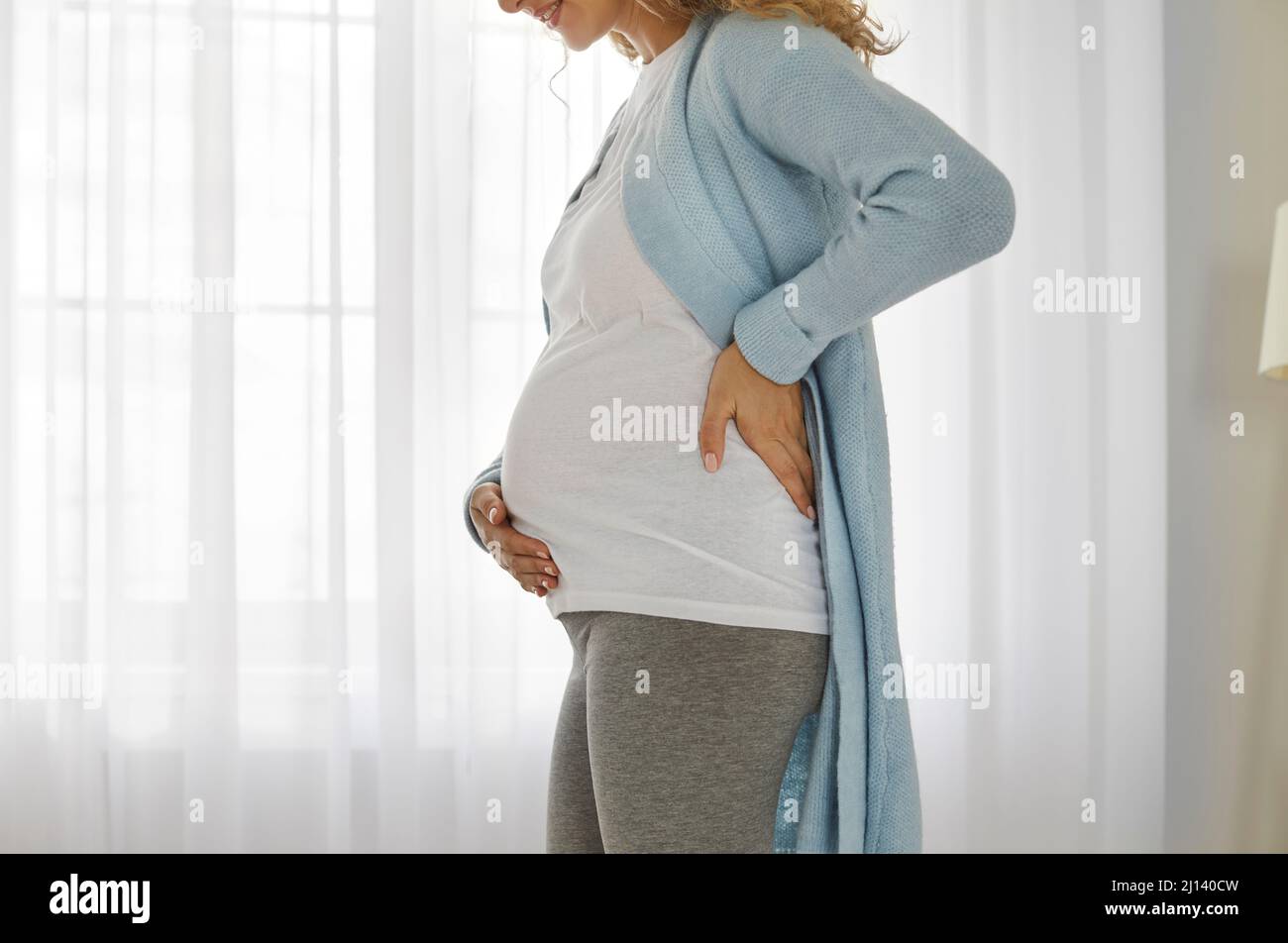 Side view of a happy beautiful pregnant woman who is holding her hand on her abdomen Stock Photo