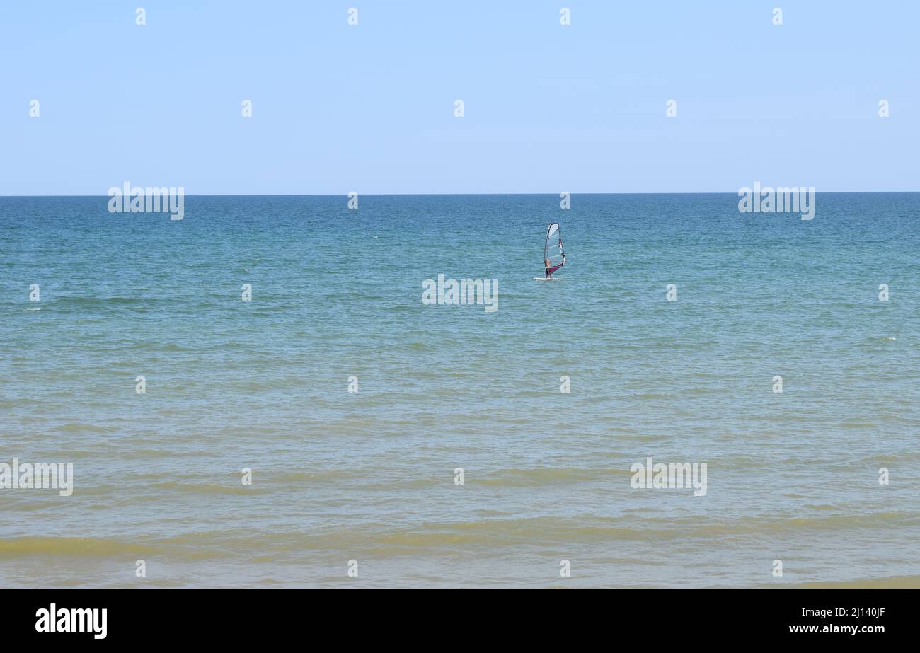 A windsurfer rides on a board with a sail. Active vacation at the sea. Azov sea, Russia - July 25.2021 Stock Photo