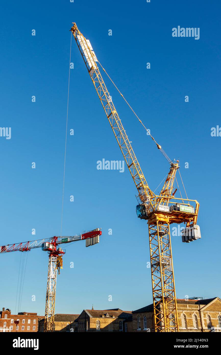 Two mechanical cranes towering above an urban construction site, the