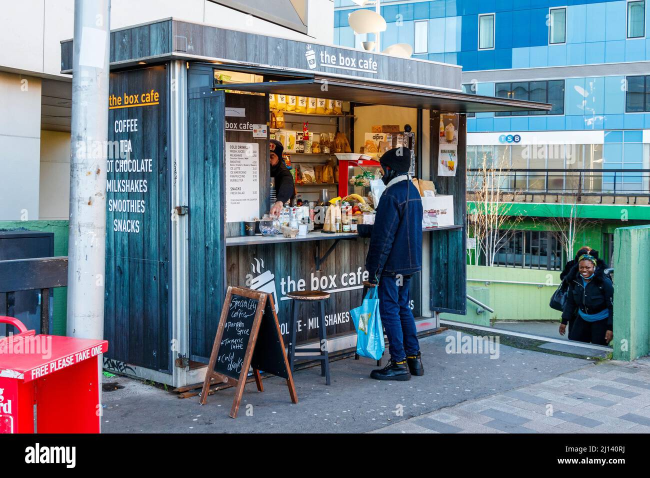 A customer at the Box Cafe, a small hut offering drinks and snacks outside Archway station in North London, UK Stock Photo