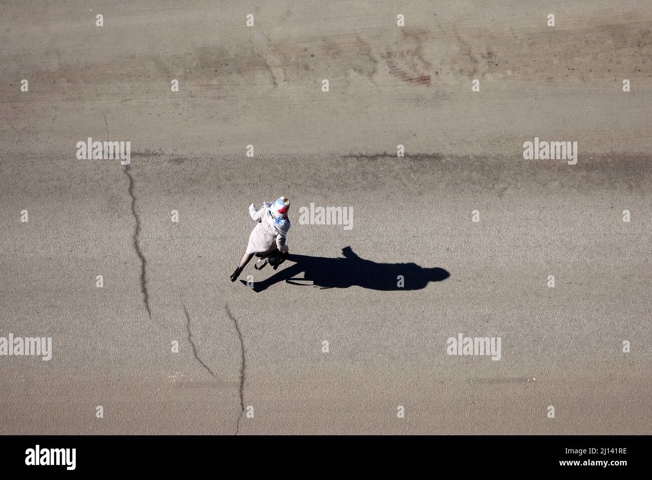Running woman crossing the street, top view. Long shadow on asphalt, concept of road safety Stock Photo