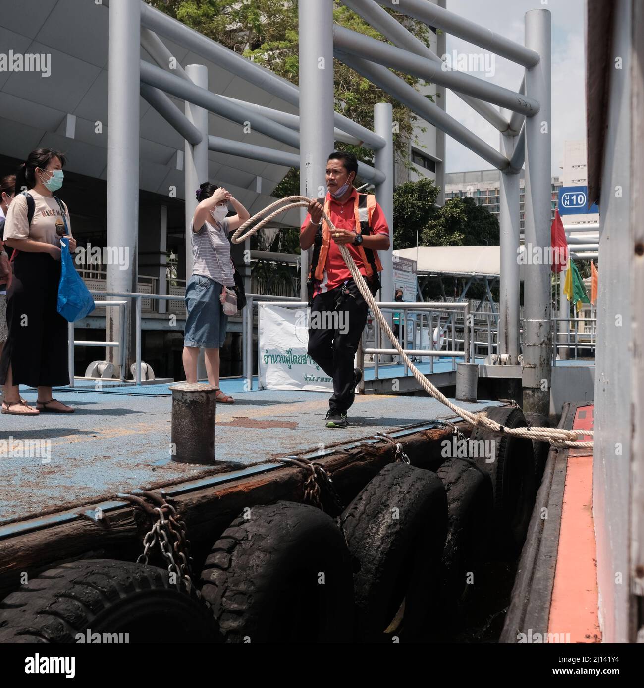 Worker on Orange Flag Express Boat Seaman Boatswain man on the ropes