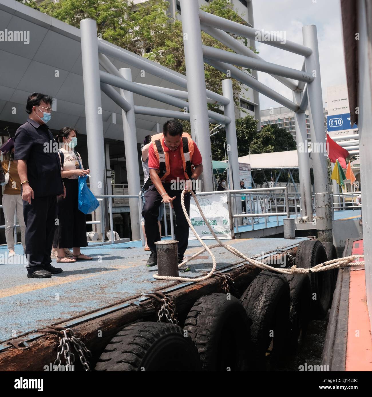 Worker on Orange Flag Express Boat Seaman Boatswain man on the ropes