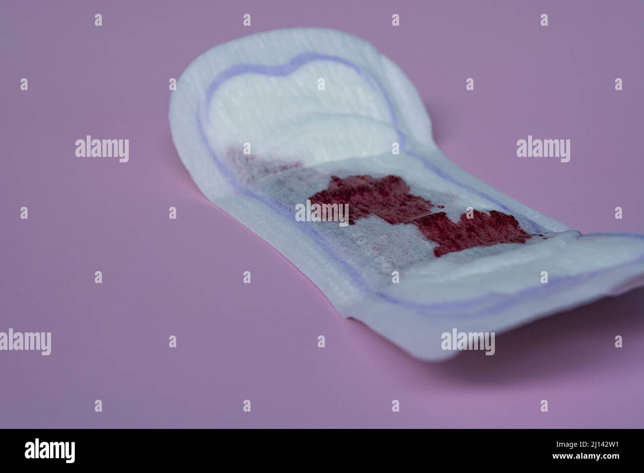 Menstrual blood on a sanitary pad on pink background. Woman hygiene