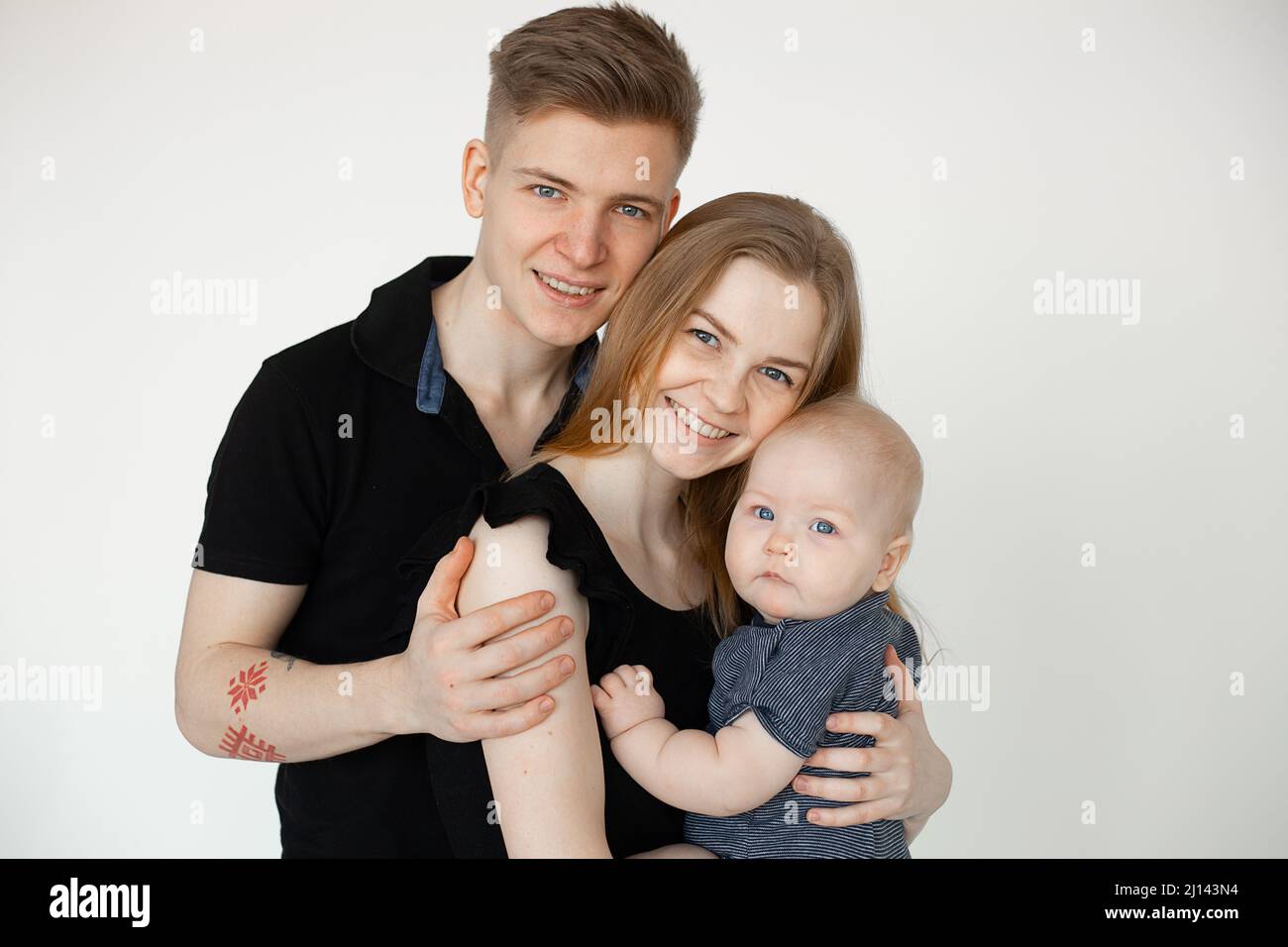 Studio shot portrait of glad spouses, parents, family, man with tattoo on arm, woman, child. Bounding goals. Close up Stock Photo