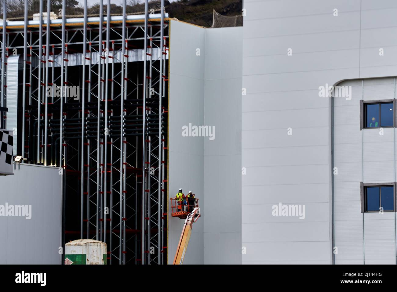 Pamplona, Spain March 22, two people climbed in a crane doing dangerous work on a facade Stock Photo