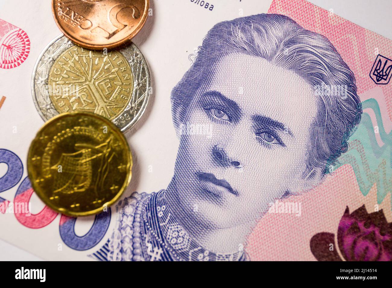 In this photo illustration, euro coins and 200 Ukrainian Hryvnias banknote with the image of Lesya Ukrainka are seen displayed. Stock Photo