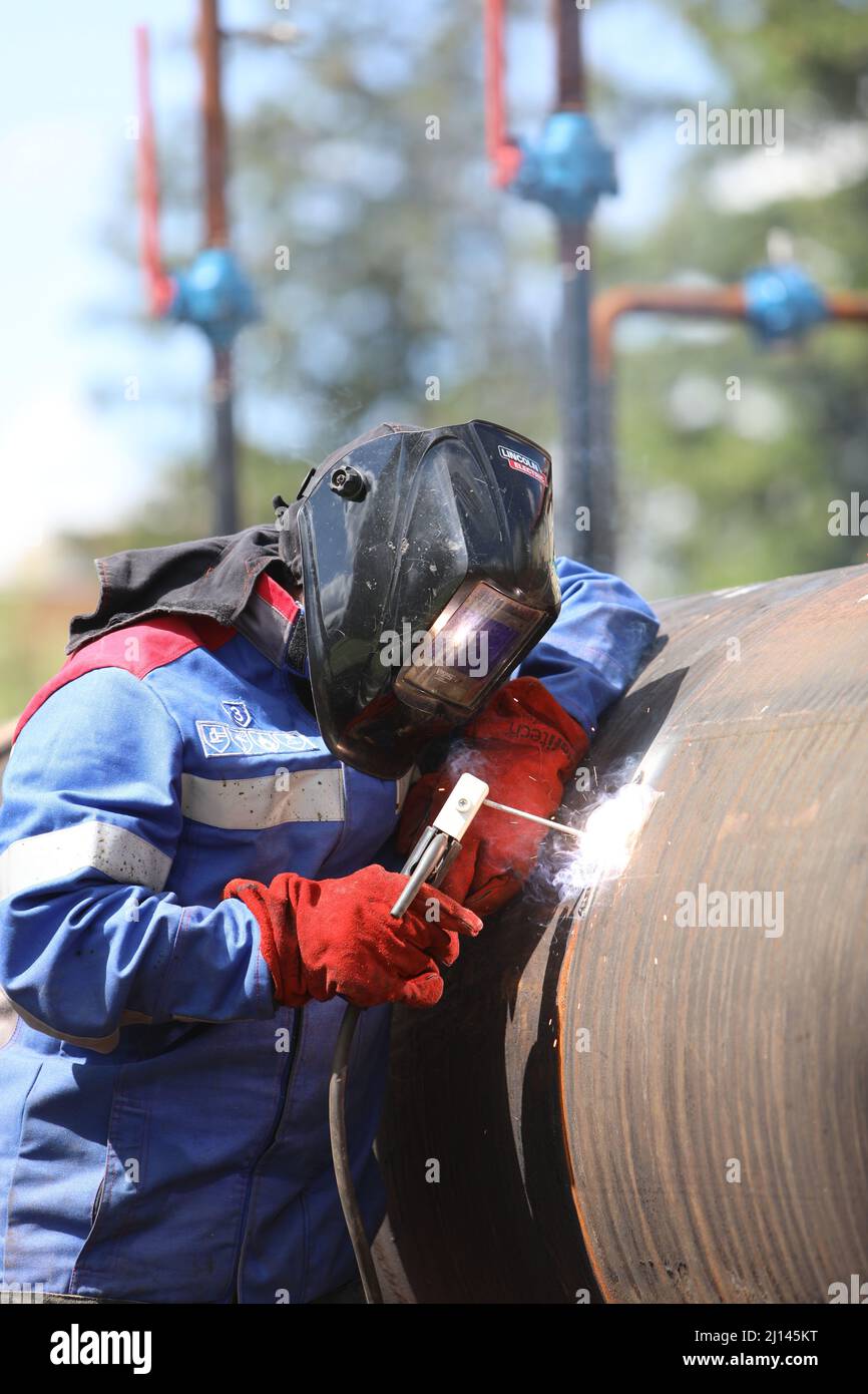 Male welder works. Welding joint of large diameter pipe. High pressure