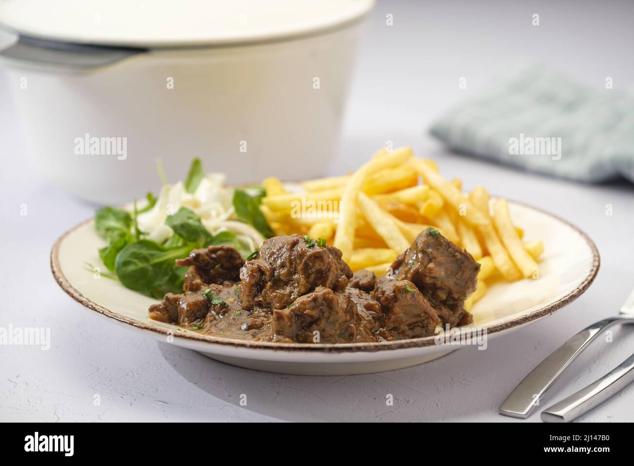 Closeup shot of typical Belgian beef stoofvlees stew with french fries