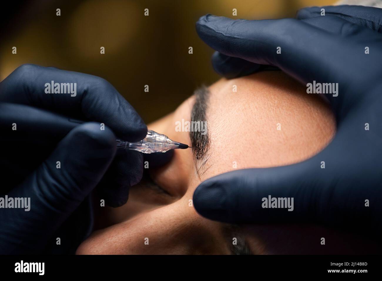 Microblading process by beauty master. Professional cosmetologist making permanent makeup on woman's eyebrow with tattoo pen machine Stock Photo
