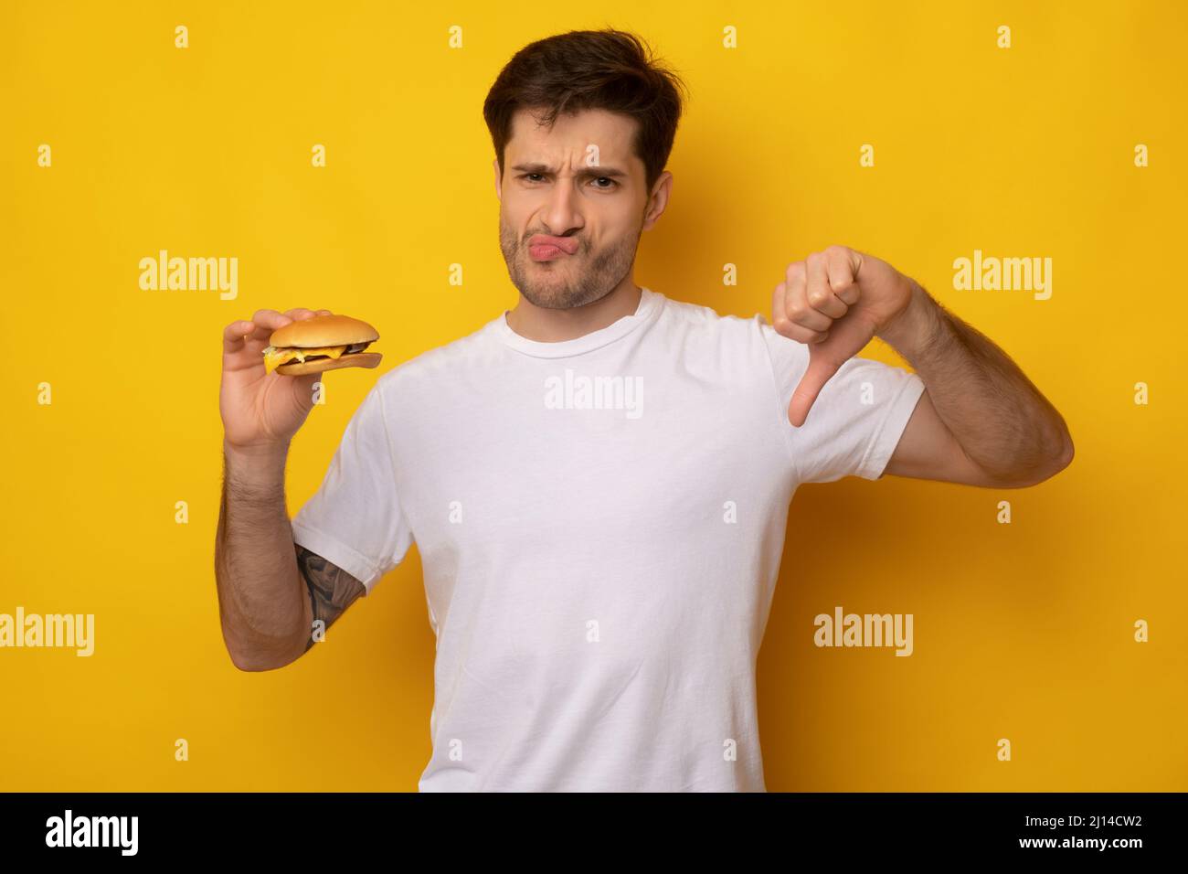 Angry Man Holding Burger Showing Thumbs Down Stock Photo