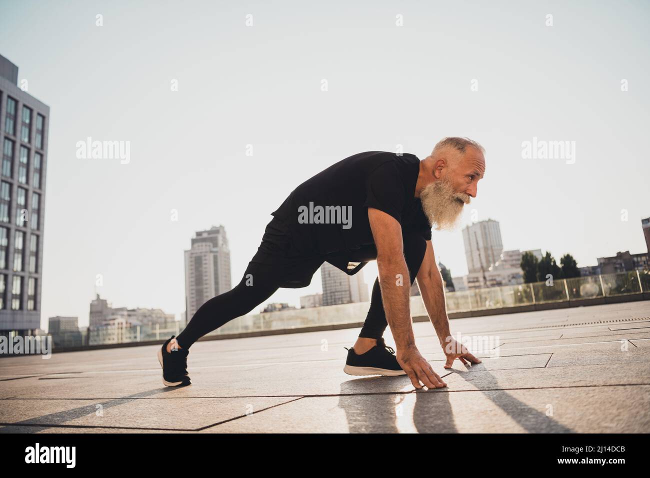 Photo of sportive energetic active pensioner runner old man stand ready sprint wear t-shirt urban town outside Stock Photo