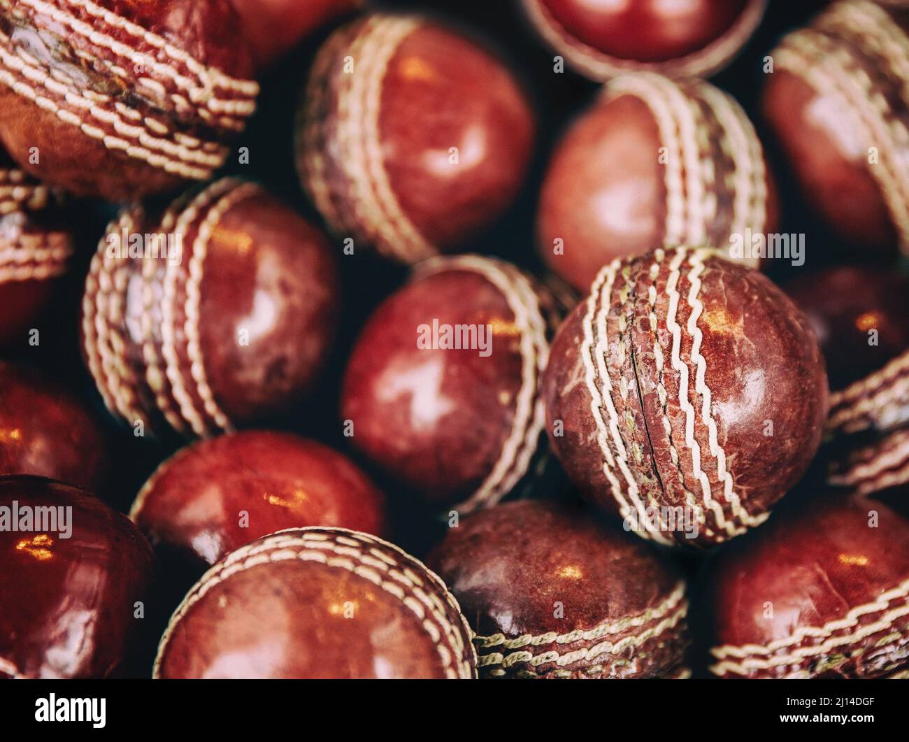 A background of vintage red leather cricket balls with white stitching. Retro style processing. Stock Photo