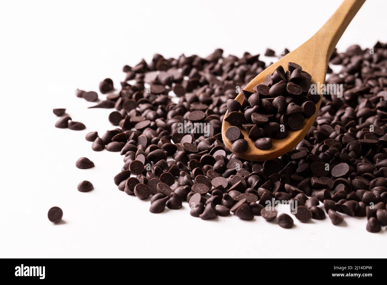 Close-up of wooden spoon with chocolate chips against white background Stock Photo