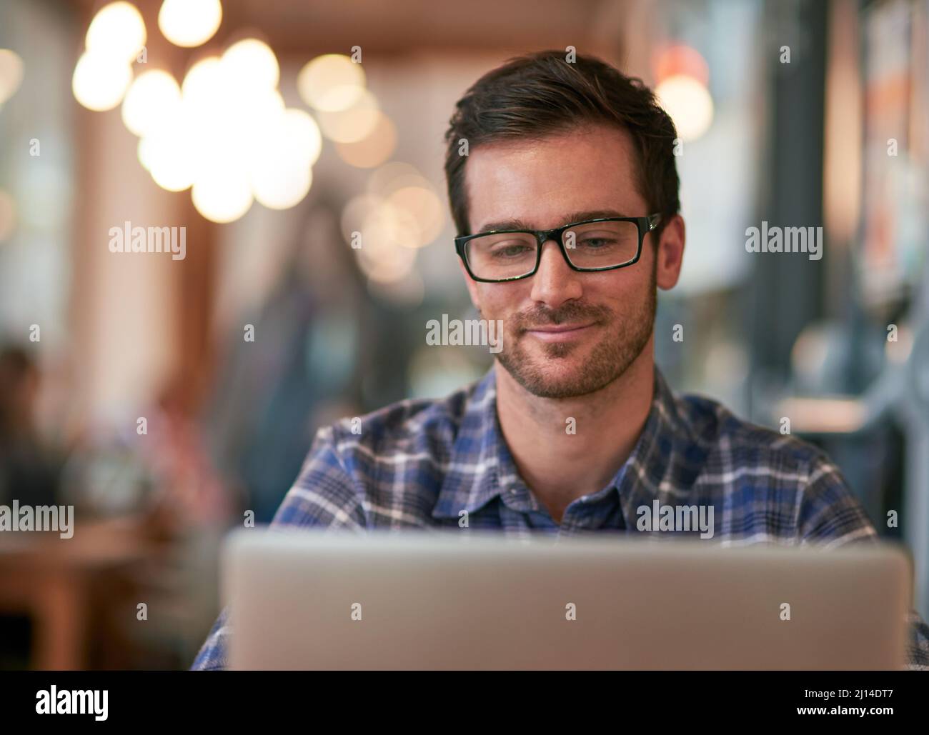 The free wifi here makes it a no brainer. Shot of a young man using his laptop while sitting in a coffee shop. Stock Photo