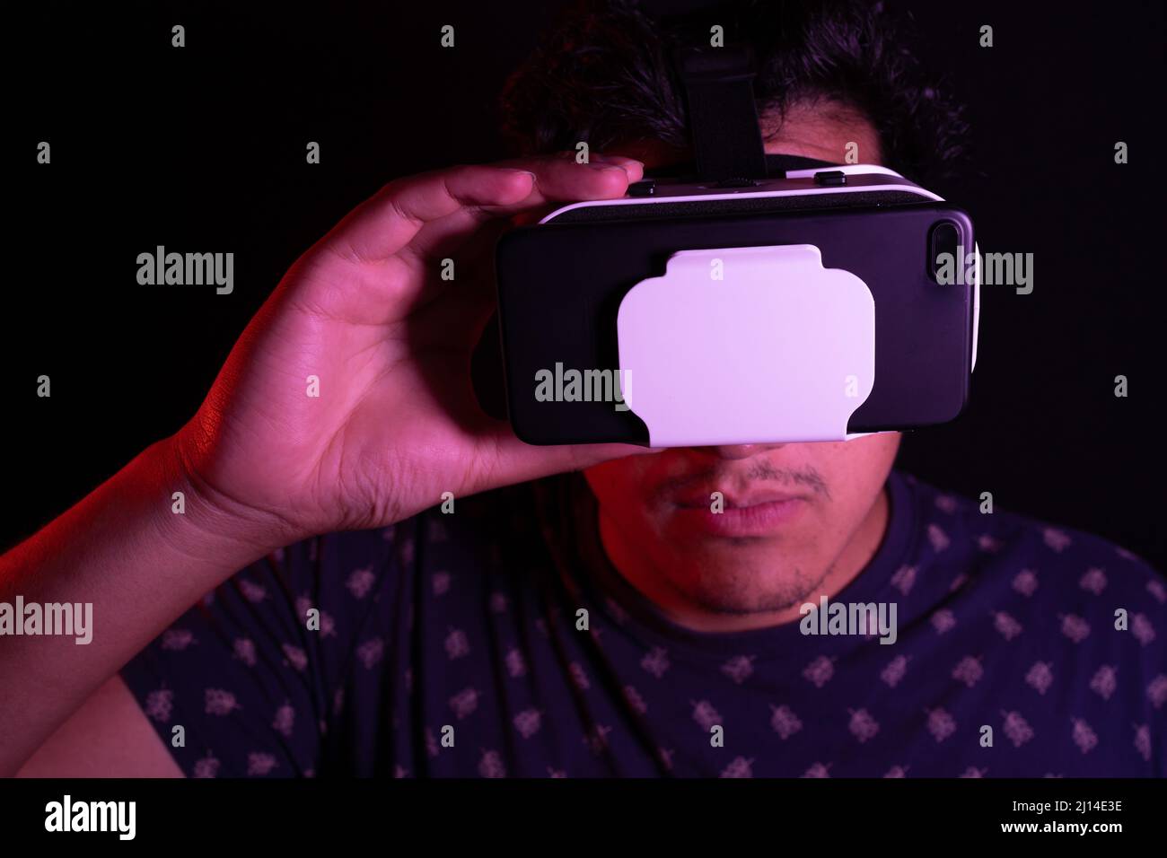 Young latin man using Virtual Reality VR Headset 3D Glasses. Dark backdrop. Low key. Stock Photo