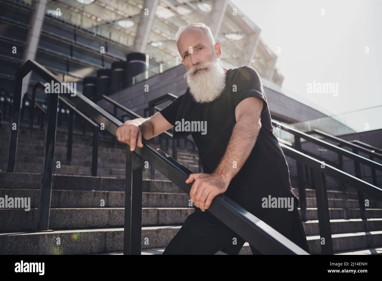 Portrait of attractive virile sportive healthy grey-haired man sportsperson standing on stairs fresh air spending time outdoors Stock Photo