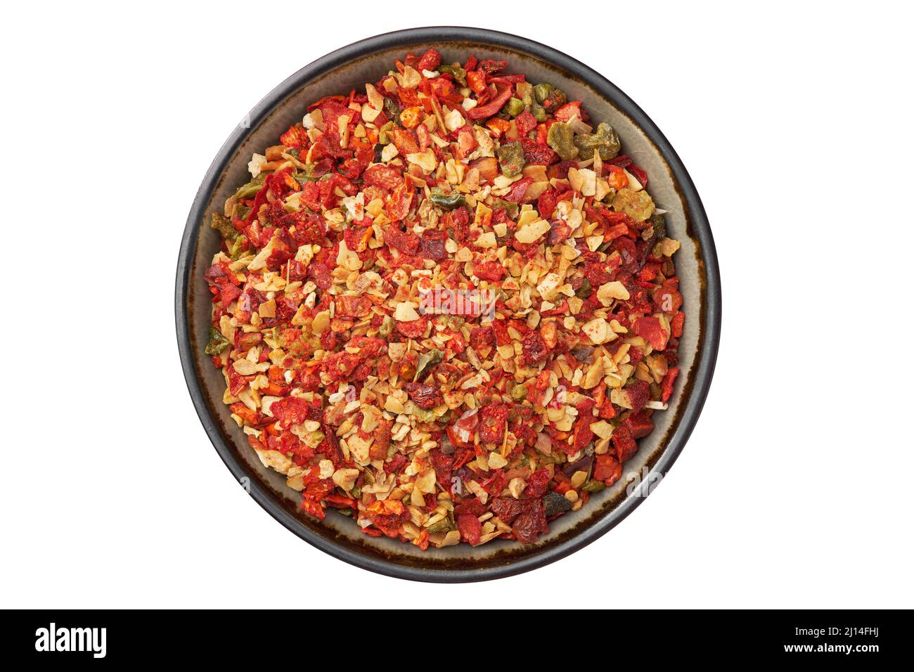 Bowl of spice mix for cooking dishes, isolated on white. Flakes of red hot pepper, paprika, garlic, onion. Dried seasoning closeup. Top view. Stock Photo