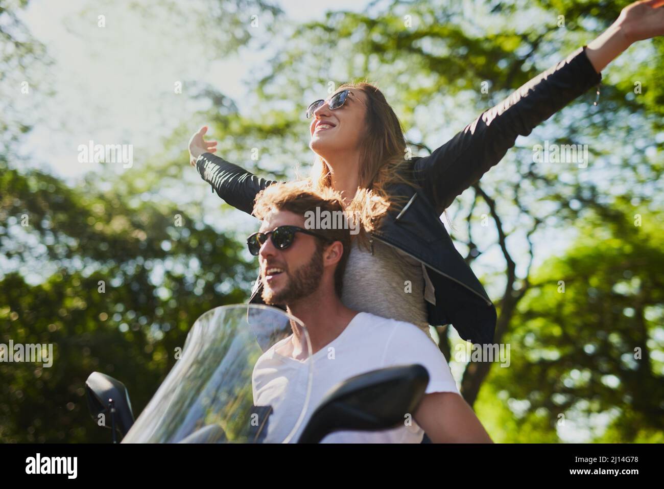 Born to wander, born to roam. Cropped shot of a young attractive couple riding a scooter around town. Stock Photo