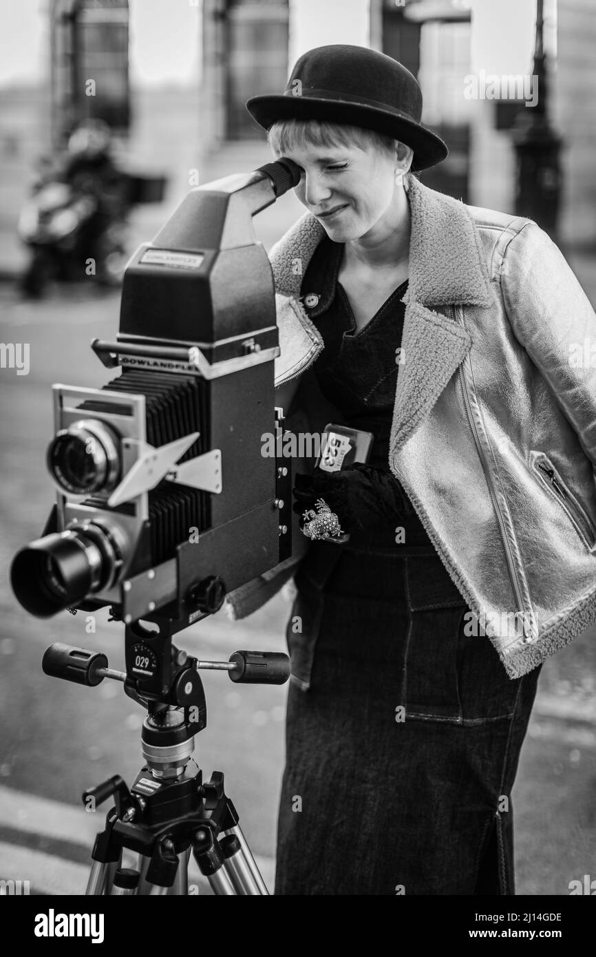 A black and white image of a stylish lady posing with a vintage camera ...
