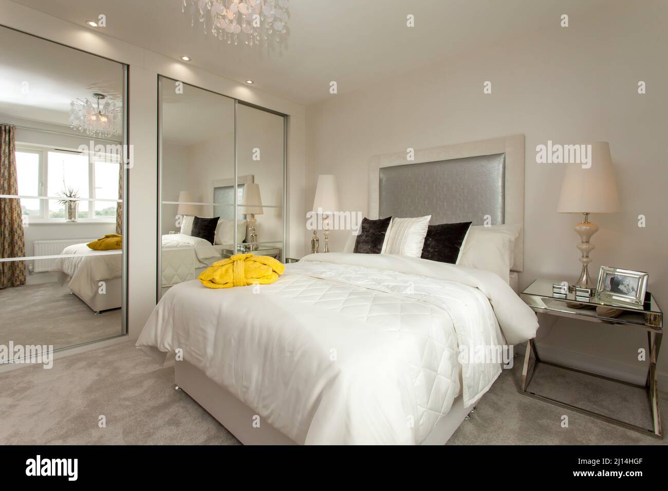 Bedroom in modern home, mirrored wardrobes,white bedspread,spacious light room, Stock Photo