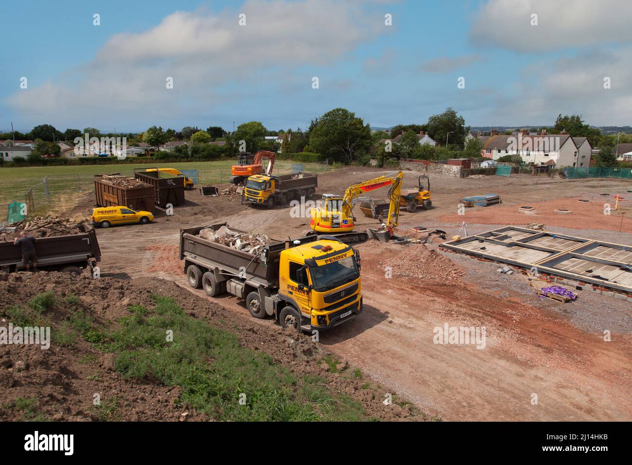 A new build building site in progress, trucks removing rubble from the site, diggers at work. Stock Photo