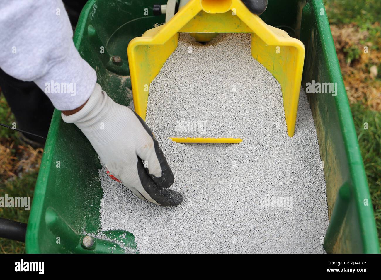 A man pouring lawn fertilizer in a barrel Stock Photo