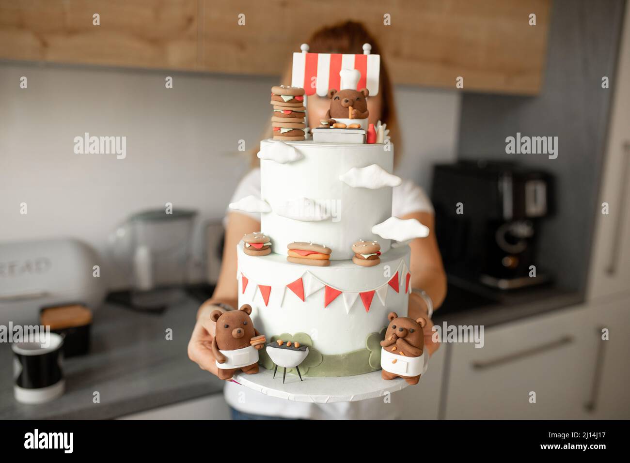 Woman standing at kitchen and hold a big birthday cake ...
