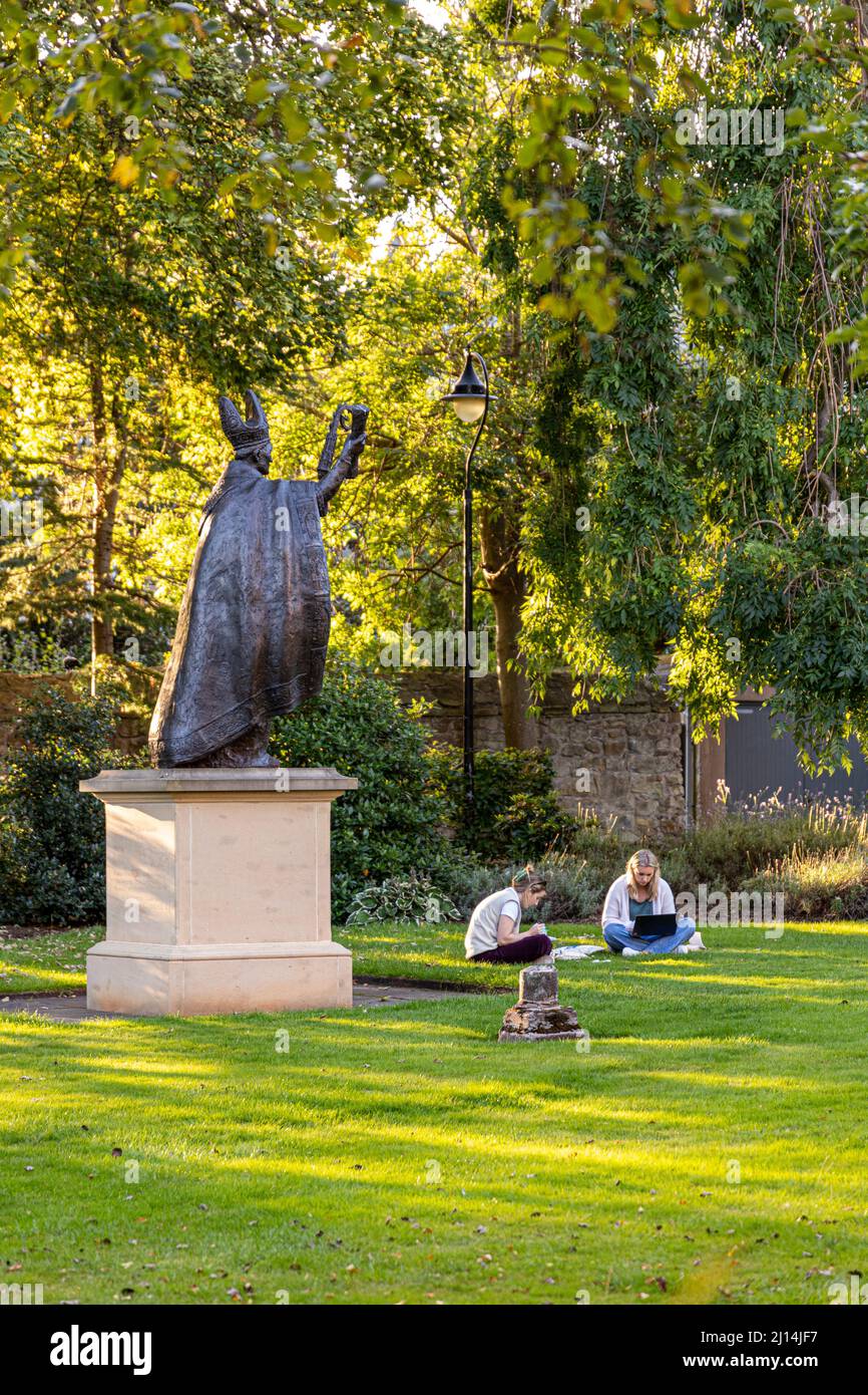 The statue of Bishop Henry Wardlaw watching over two female students studying in St Marys College Quadrangle, University of St Andrews, Fife, Scotland Stock Photo