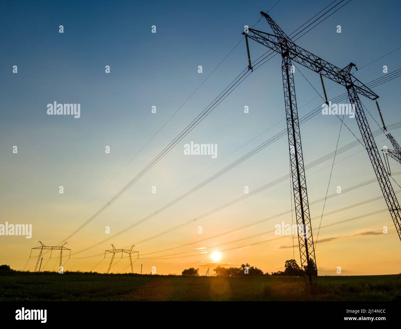 Dark silhouette of high voltage towers with electric power lines at ...