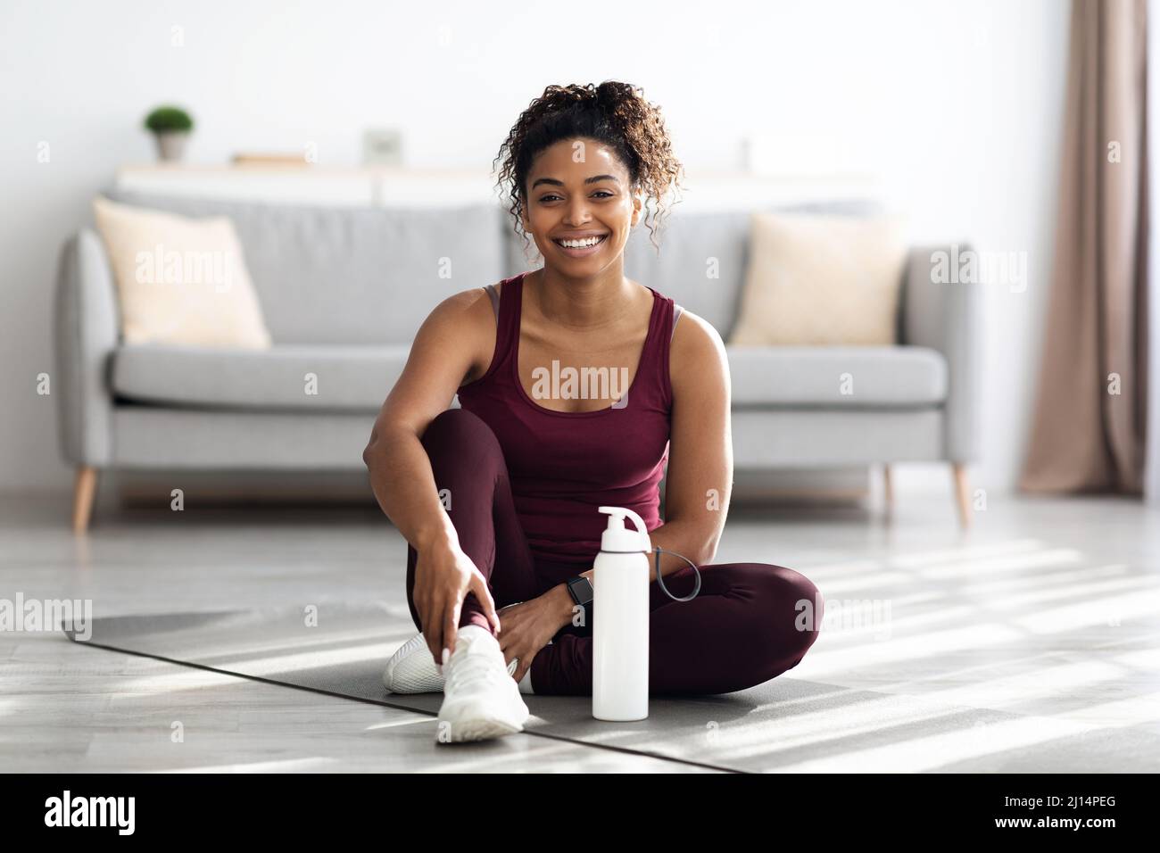 Positive sporty black lady sitting on fitness mat and smiling Stock ...