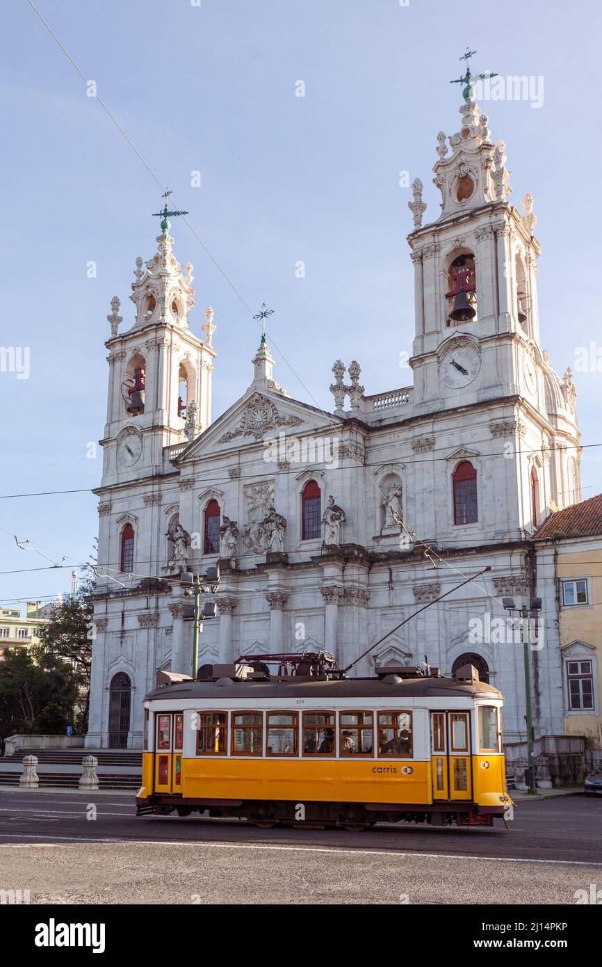 The iconic yellow Tram 28 passing in front of Basilica da Estrela, the historical neoclassical church located in the centre of Lisbon, Portugal. Stock Photo