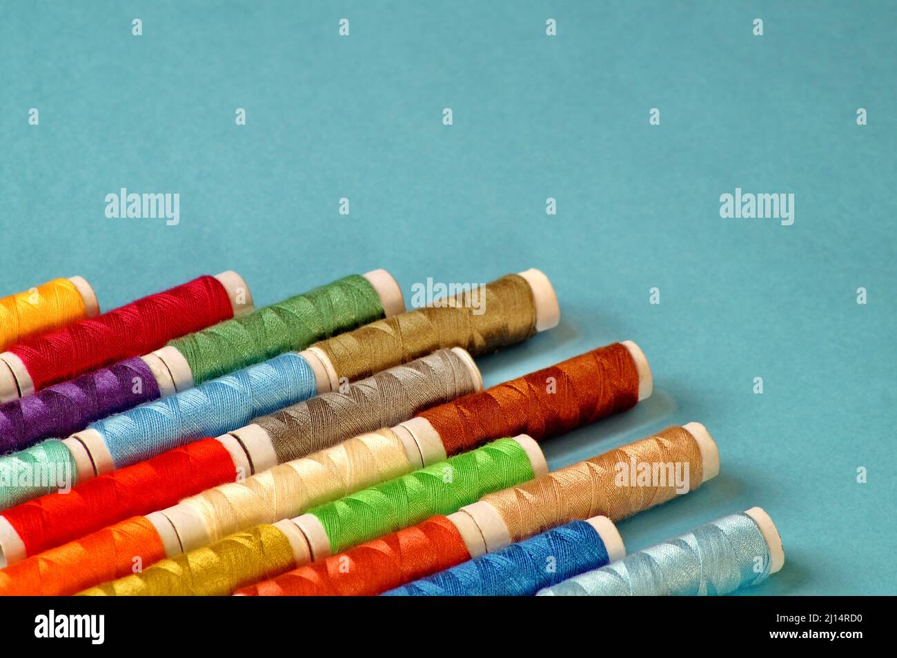 Spools of colored thread lie diagonally in the lower left corner on a ...
