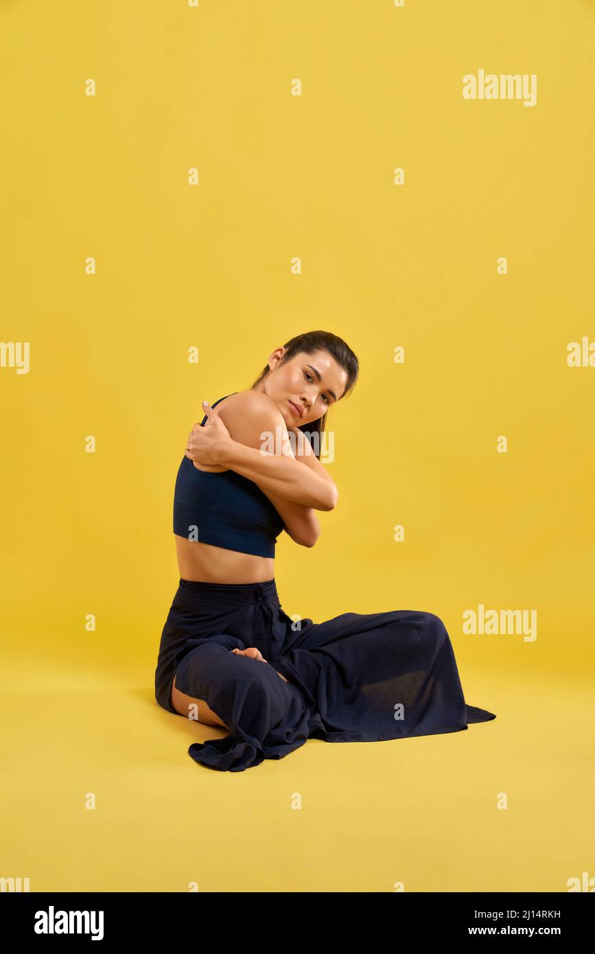 Front View Of Sporty Girl Sitting With Crossed Legs Holding By Hands 